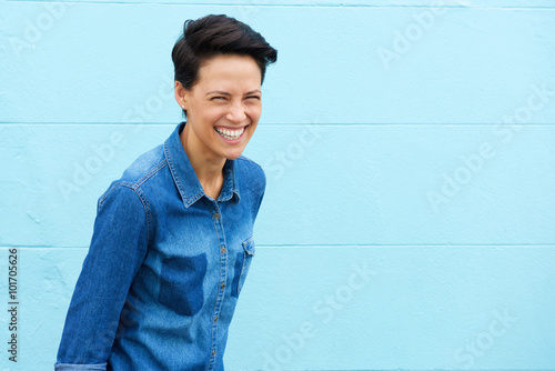 Young woman laughing against blue background