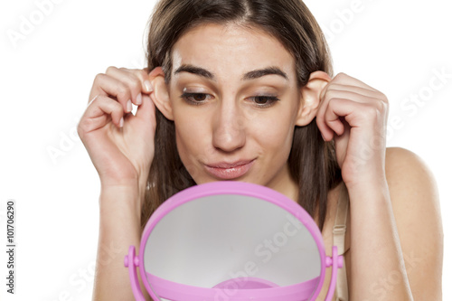 beautiful young woman looks at her ears in front of the mirror photo
