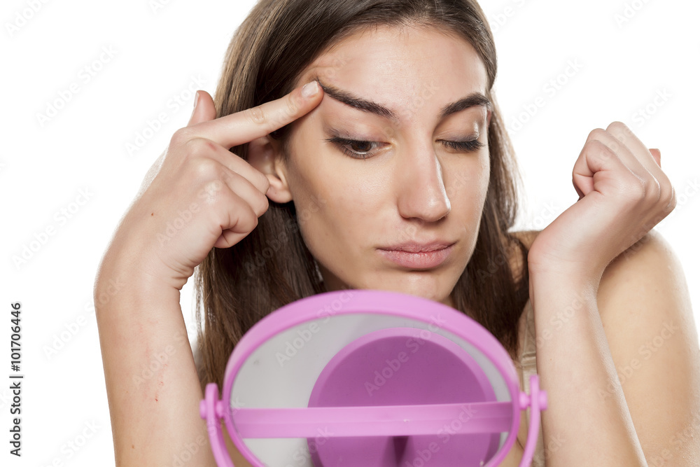 Φωτογραφία beautiful young woman tightens the skin on her face in front of the mirror