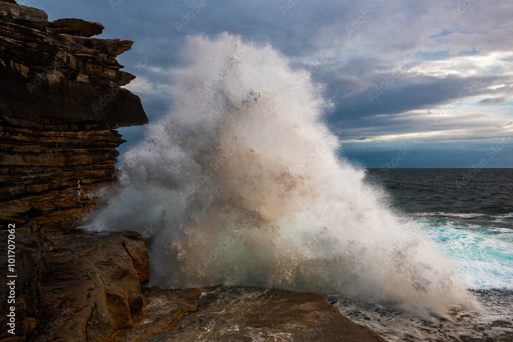 A man standing in front of the crashing wave