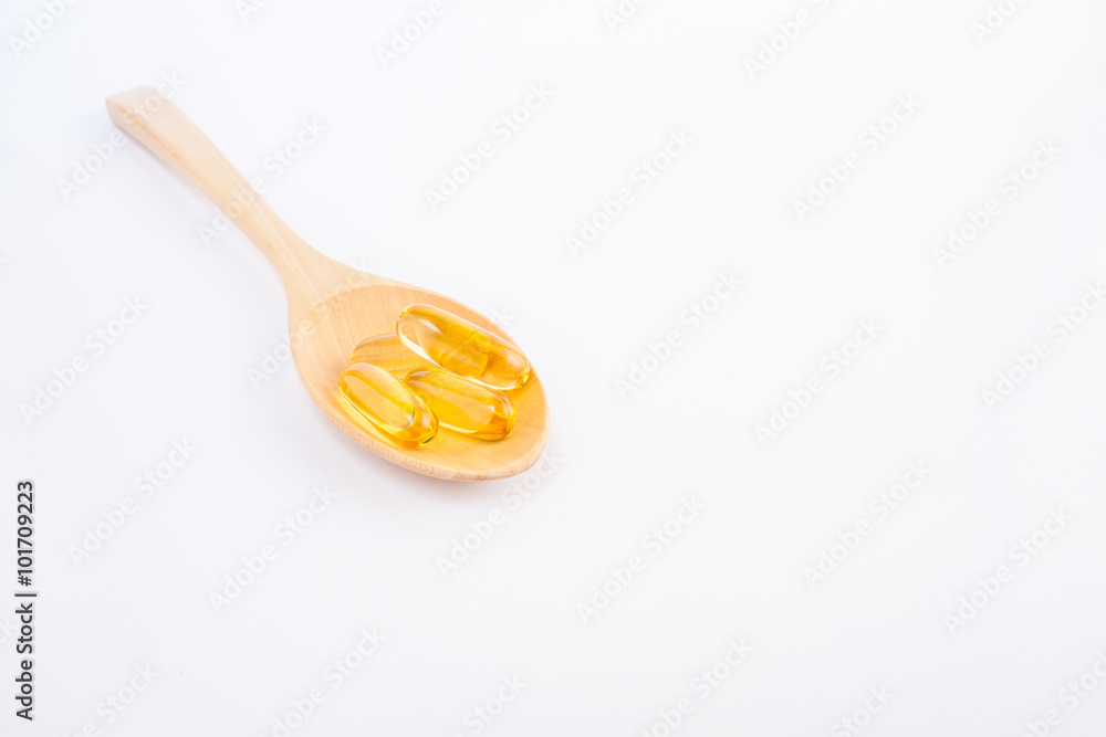 Fish oil capsule in wooden spoon on white background Fish oil capsule in wooden spoon on white background