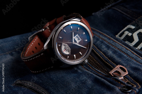 Wrist watches with brown dial on brown leather strap on blue jeans 