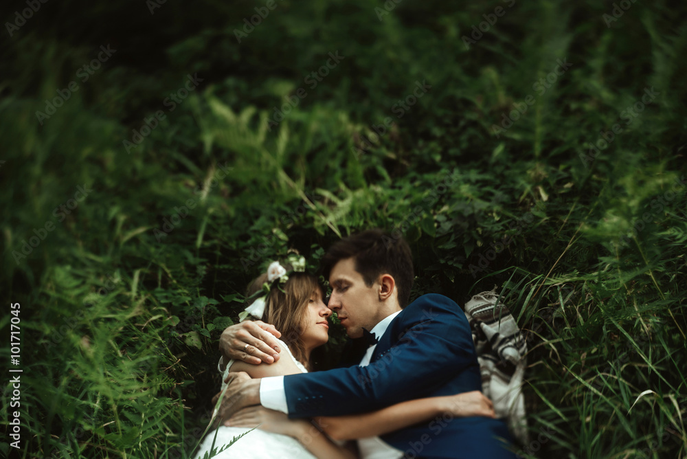 luxury happy bride and stylish groom lying on grass under sunny luxury happy bride and stylish groom lying on grass under sunny