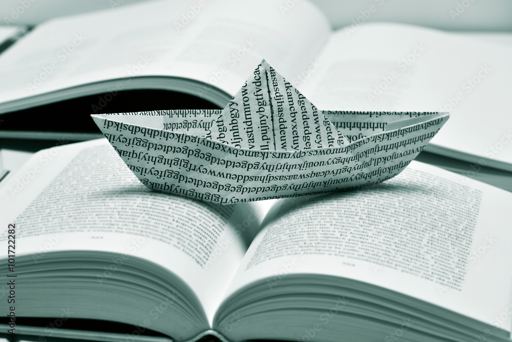 Fototapeta premium paper boat on an open book, black and white