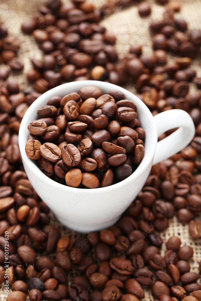 Coffee beans in cup on a sack, close up