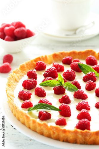 Sweet tart cake with raspberries on white wooden background