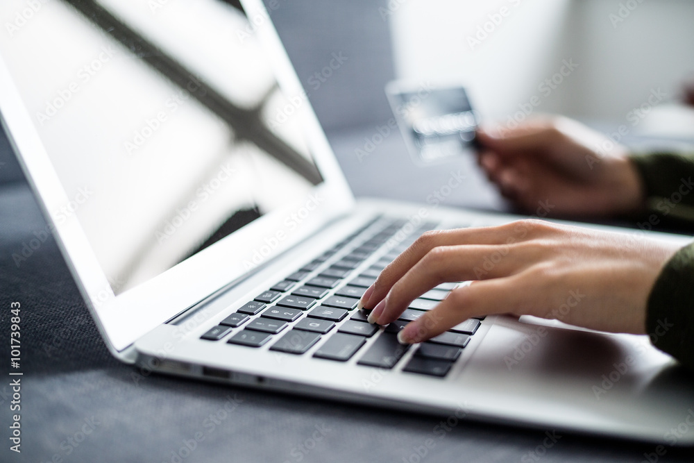 Hands holding credit card and using laptop Hands holding credit card and using laptop