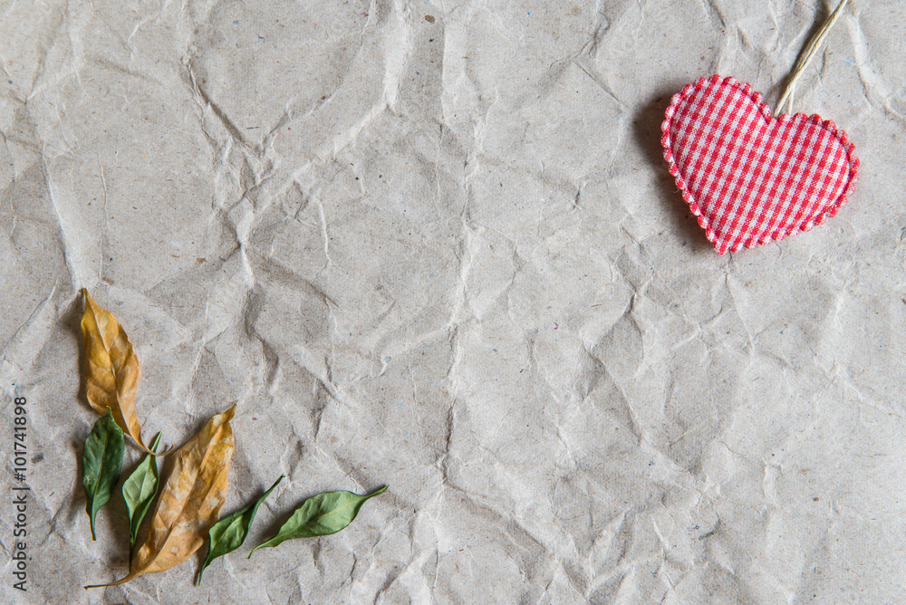 Obraz premium Beige crumpled paper with heart and withered leaves for valentin