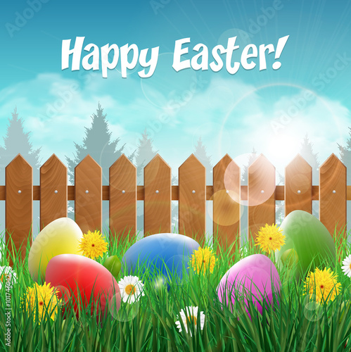 Easter card with Easter eggs on a grass field with flower wooden fence in the background.