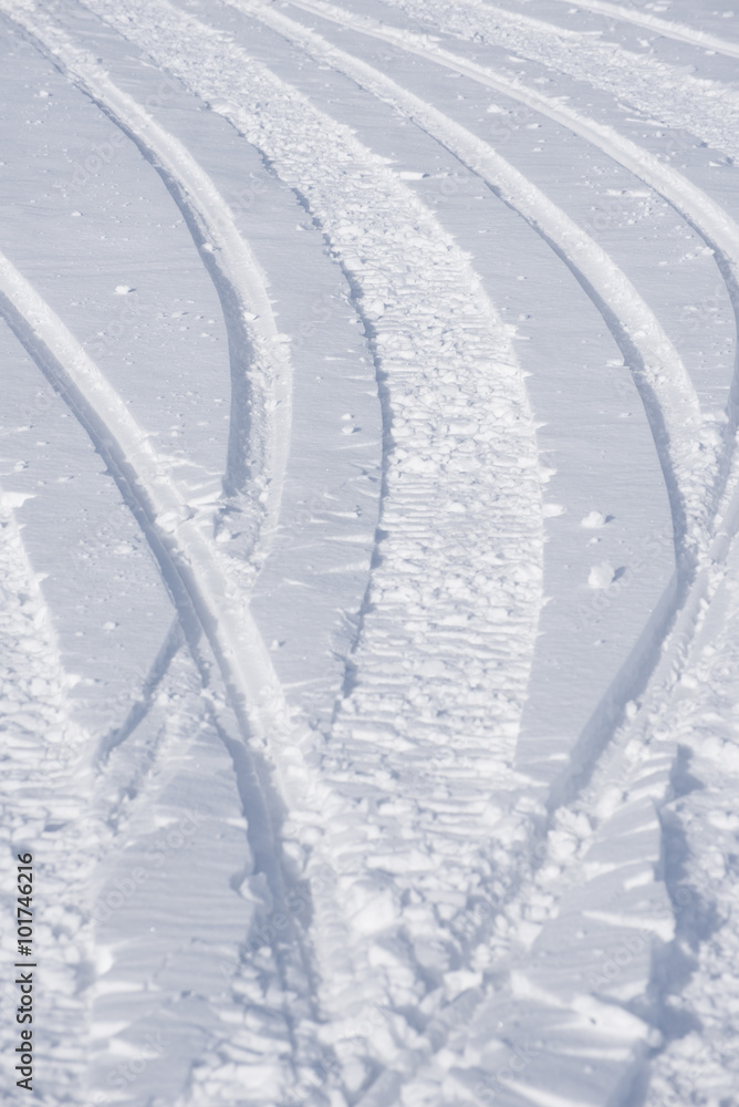 The tracks and curves from snowmobile skies cut a trail the fresh snow. The tracks and curves from snowmobile skies cut a trail the fresh snow.