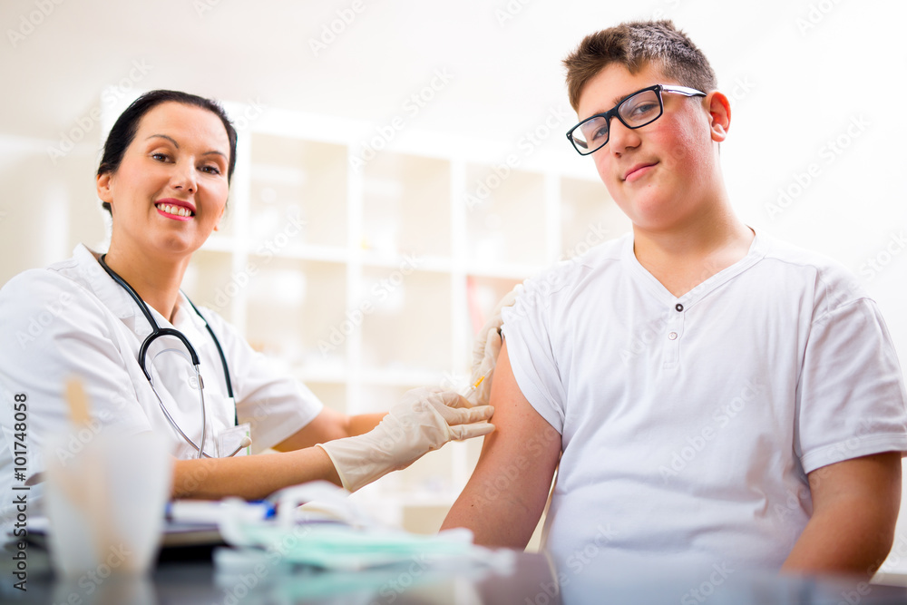 Teenage boy getting vaccination in his arm Teenage boy getting vaccination in his arm