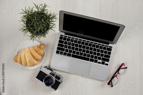 Top view of Office Table with croissant an office suplies photo