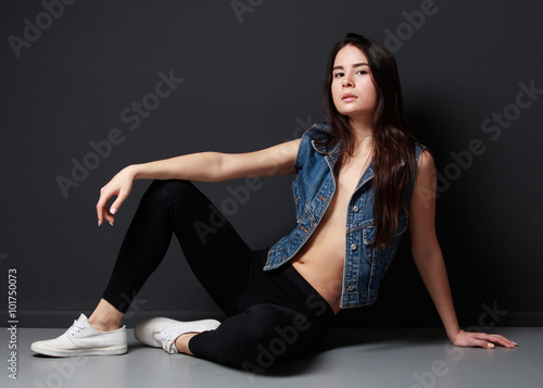 Young brunette woman sitting on the floor, cheeky pose