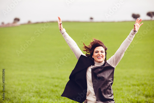 Brunette woman jumping in the countryside. Happiness concept.