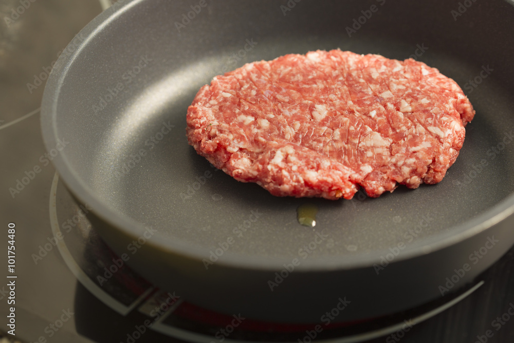 Red raw burger on a black pan close up Red raw burger on a black pan close up