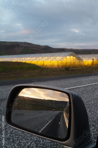 Reflections on a car mirror with an energy farm ahead during a cloudy day  Iceland
