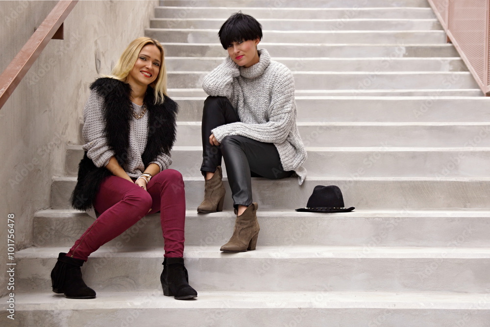 Two cute young woman sit on the stair and speaks together Two cute young woman sit on the stair and speaks together