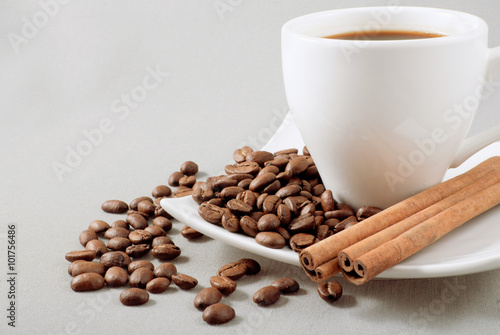 black coffee, grains and cinnamon on a grey background