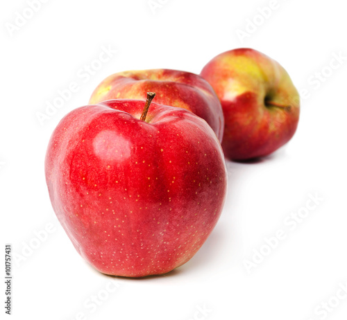 three red apples stand in one row on a white background