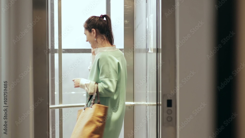Woman talking on the phone and enters the elevator Woman talking on the phone and enters the elevator