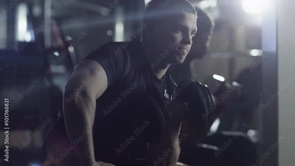 Handsome fit sporty man is exercising with heavy dumbbell in the gym. Shot on RED Cinema Camera. Handsome fit sporty man is exercising with heavy dumbbell in the gym. Shot on RED Cinema Camera.