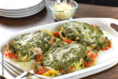 Tasty baked chicken breasts are covered with basil pesto sauce, fresh cherry tomatoes, yellow bell peppers and topped with melted parmesan cheese.