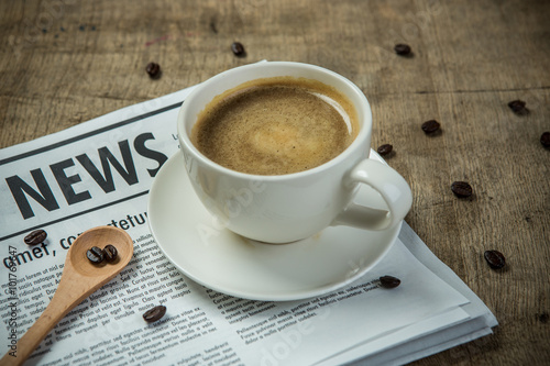 A newspaper and a cup of coffee on a wooden table