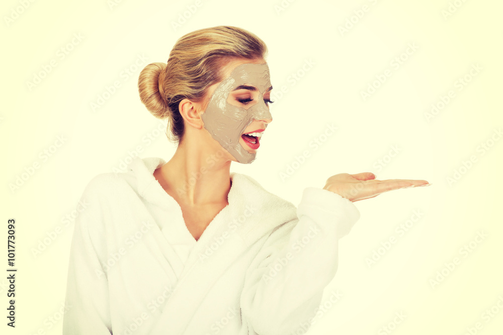 Young woman with facial mask holding something on her hand Young woman with facial mask holding something on her hand