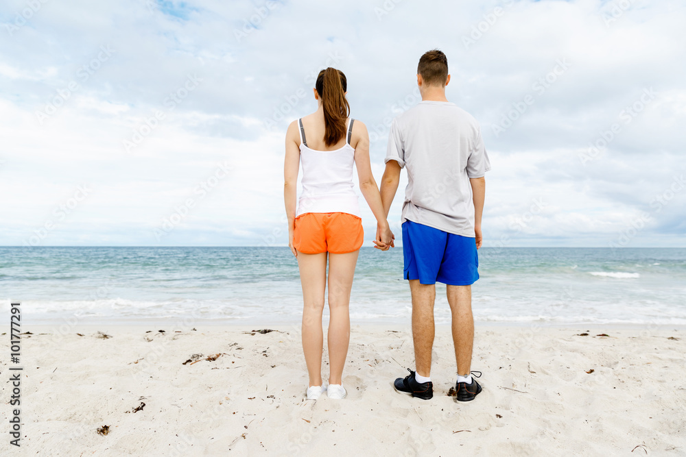 Young couple looking thoughtful while standing next to each other on beach Young couple looking thoughtful while standing next to each other on beach