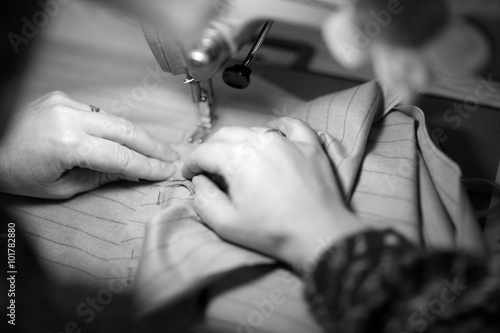 Tailor's hands hemming on a sewing machine