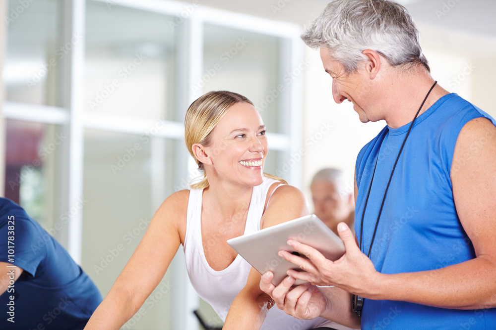 Trainer mit Tablet Computer redet mit Frau Trainer mit Tablet Computer redet mit Frau