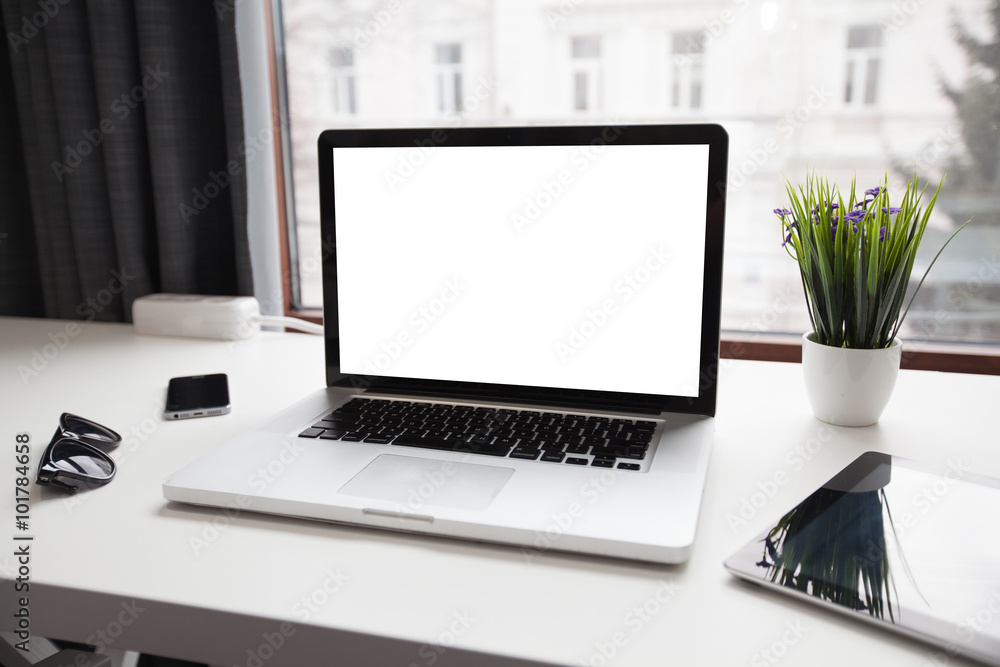 Fototapeta premium Tablet, laptop and a smart phone on table next to a window