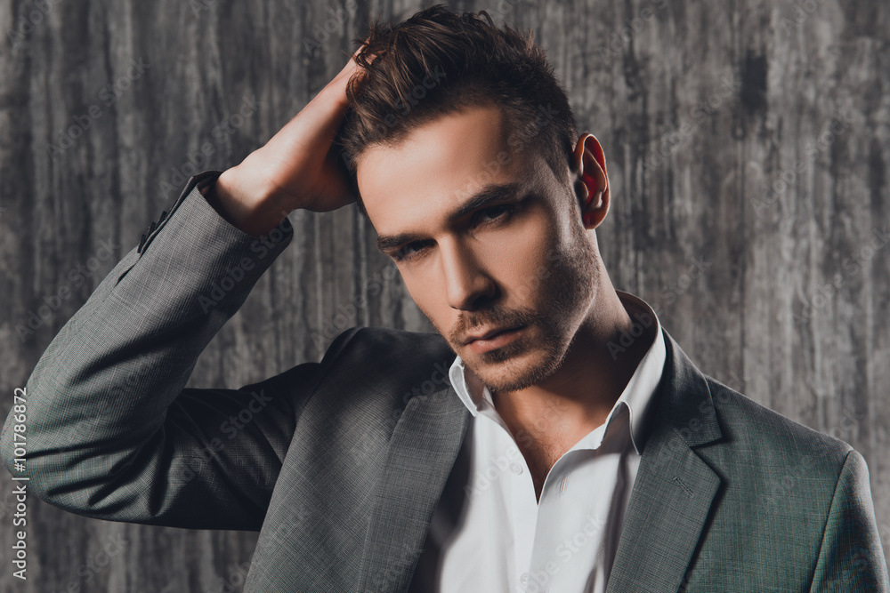 Obraz premium Attractive rigid man in business suit on the grey background