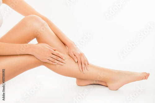 Closeup photo of cute pretty young woman touching her legs