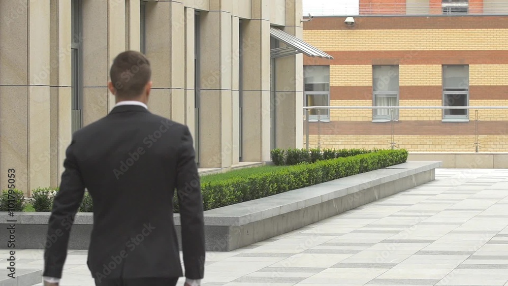 back view of walking businessman on the road over beautiful landscape. slow motion back view of walking businessman on the road over beautiful landscape. slow motion