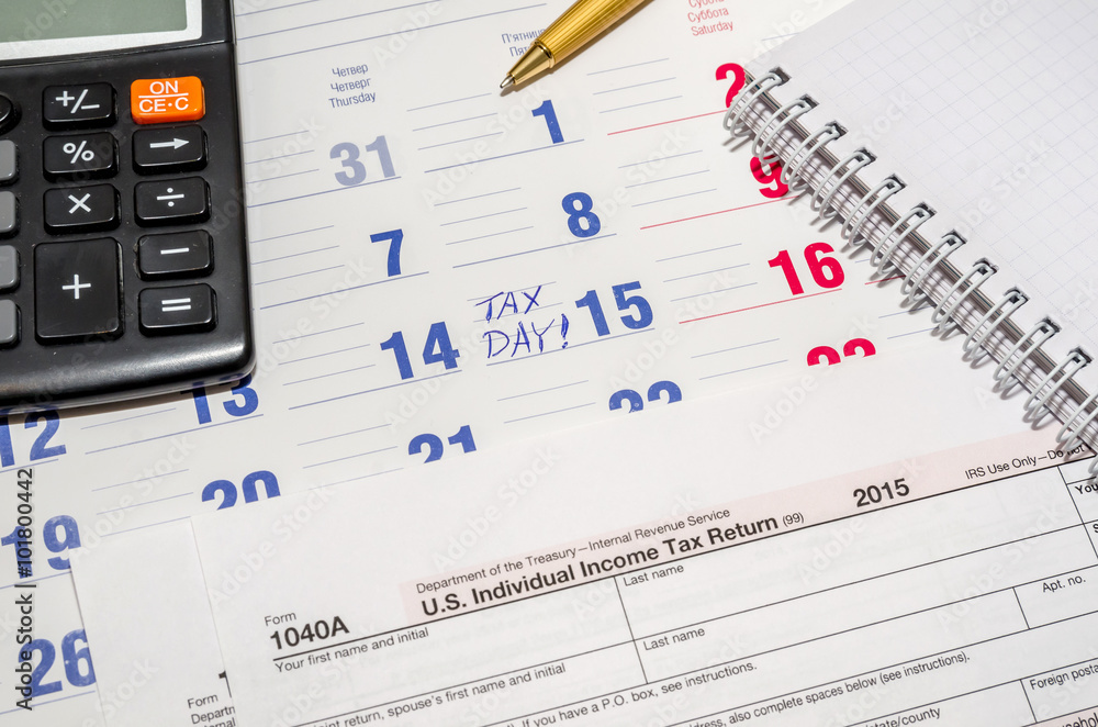tax form with calculator, pen, notepad above paper calendar tax form with calculator, pen, notepad above paper calendar