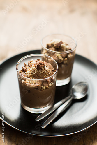 Vegan chocolate mousse (pudding) in a glass bowl with a silver spoon. Rustic tablecloth in the background, close up. 