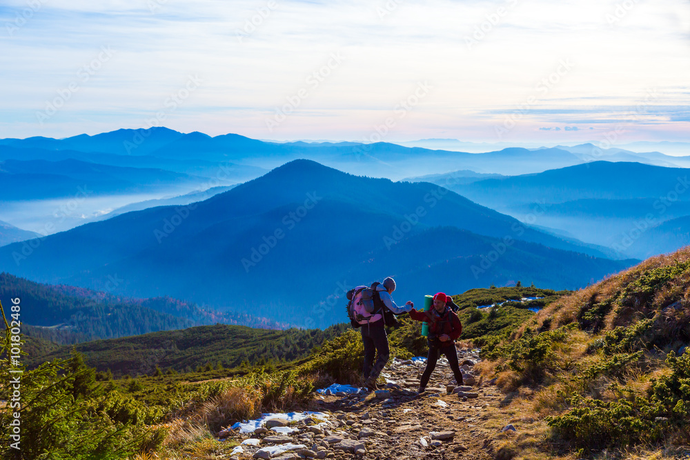 Two Hikers helping each other on Mountain Trail