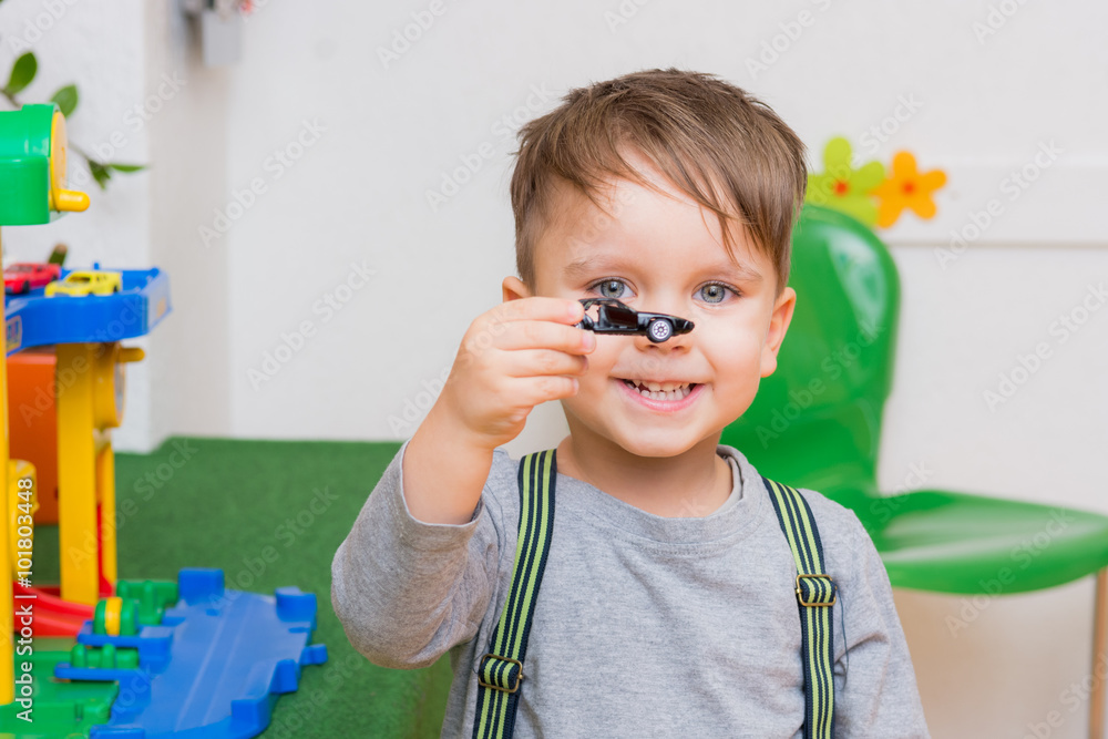 Fotografie kleiner junge spielt mit autos im kindergarten