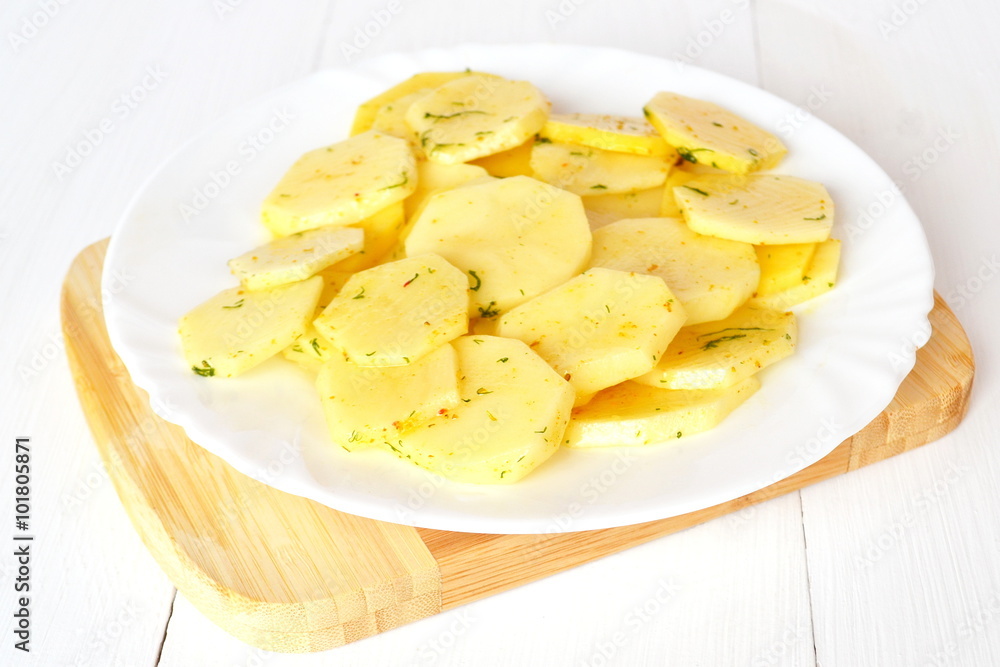 Diced potatoes with spices on a white plate on a board Diced potatoes with spices on a white plate on a board