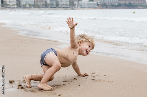 Little boy trying yoga on the beach.
