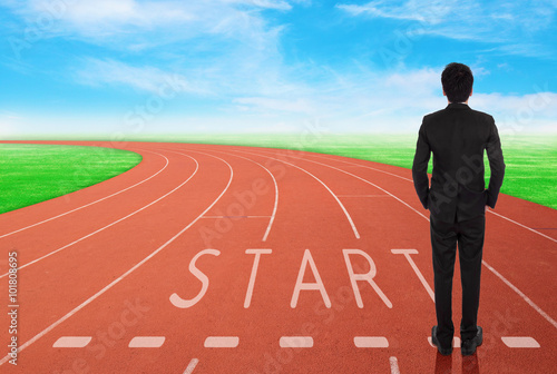 businessman standing on running track and looking to goal