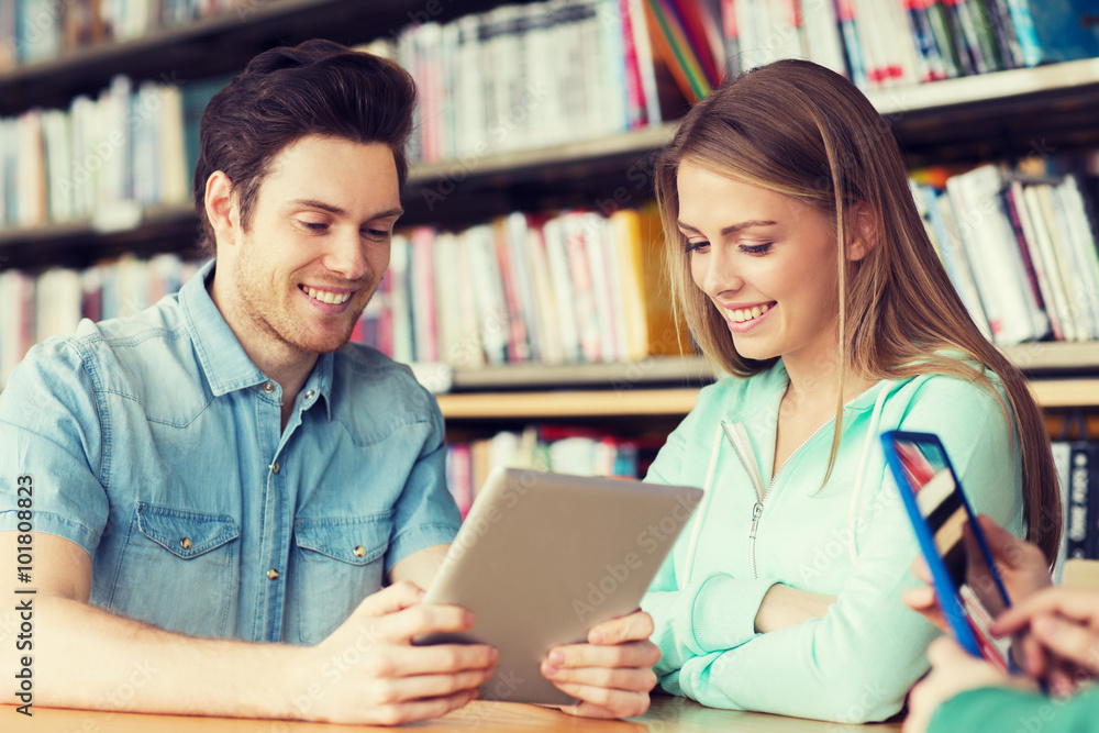 happy students with tablet pc in library happy students with tablet pc in library