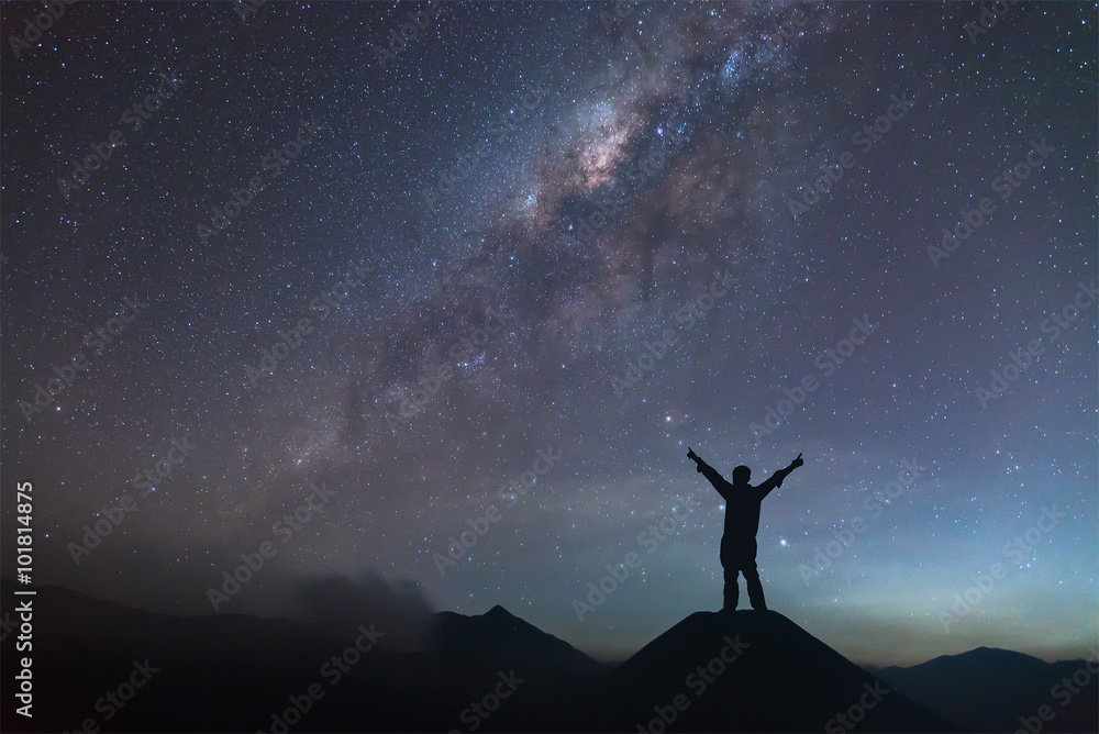 Man is spreading hand on hill and seeing the Milky Way.