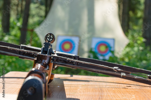 Crossbow lying on a table with targets at backgroung photo