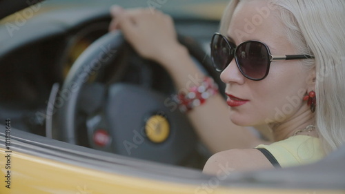 Blonde in sits behind the wheel of cabriolet photo