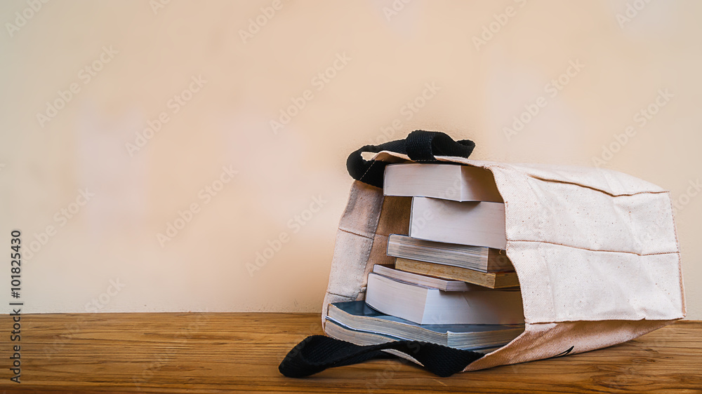 Fototapeta premium books inside cloth bag on wood table,vintage style.