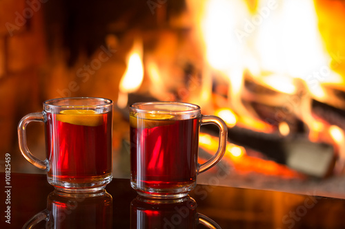 Two cups of hot drink in front of warm fireplace. Magical relaxed cozy atmosphere near fire.