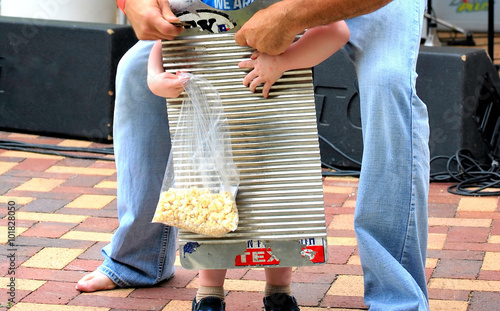 Boy playing washboard zydeco music with his dad in concert. photo