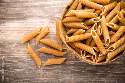 Macaroni on the bowl, wooden background.